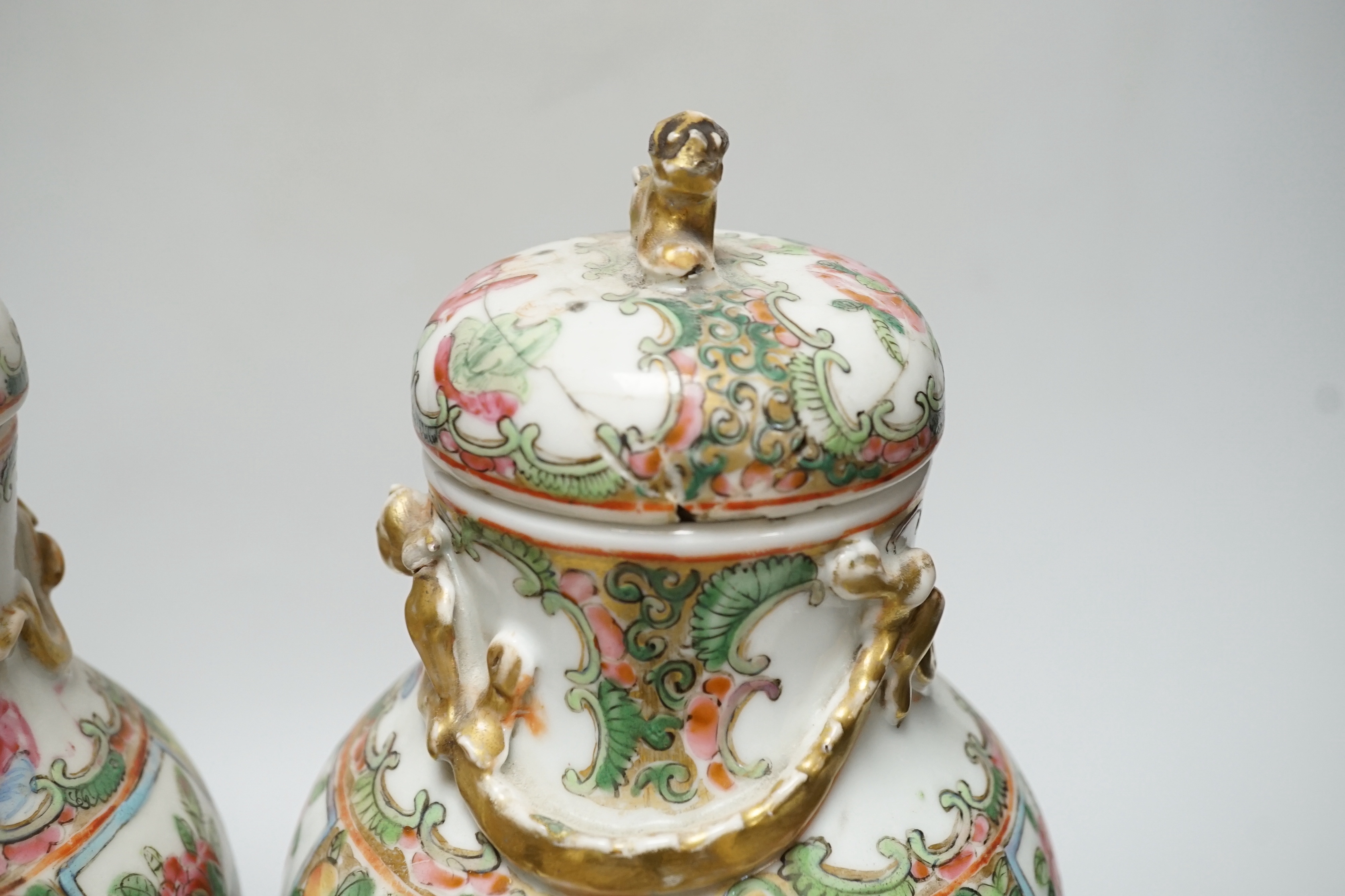 A pair of Chinese famille rose Canton baluster jars and covers with lion dog finials, 32cm high